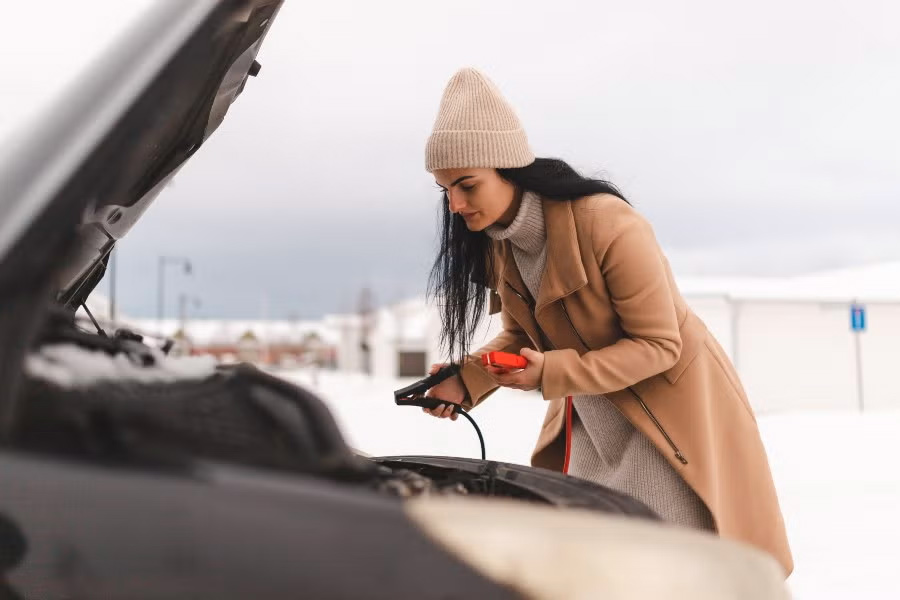 Connecting car battery cable by a cute girl